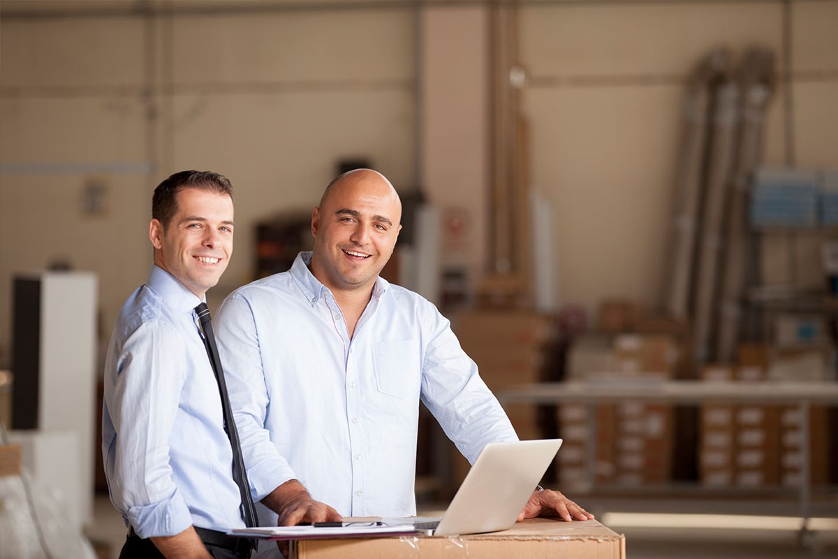 Businessmen meeting in warehouse with laptop